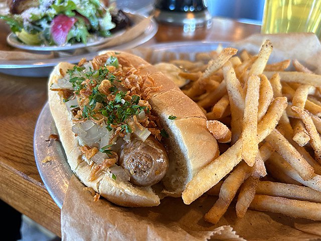 Lamb sausage in a bun with fries.