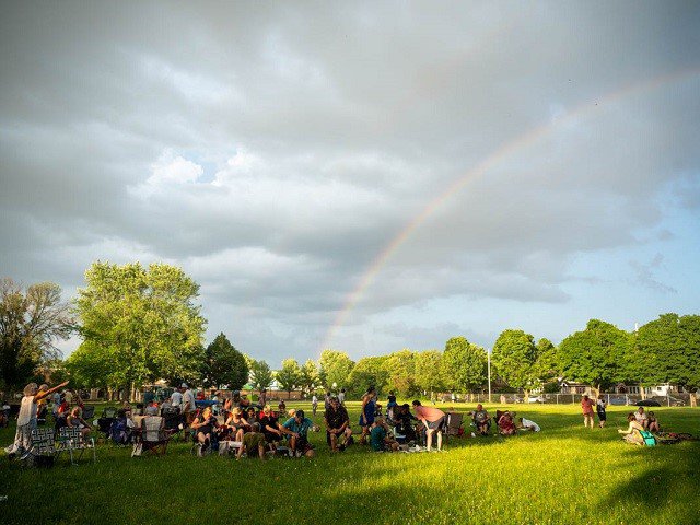 A rainbow over a field of people.