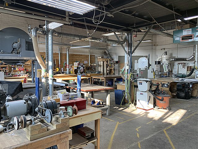 A workshop with a lot of equipment for making things and vacuum tubes for taking away dust.