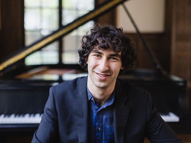 Maxim Lando in front of a piano.