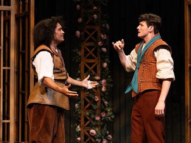 Benvolio gestures to his friend and cousin Romeo, who is signing back to him in ASL.