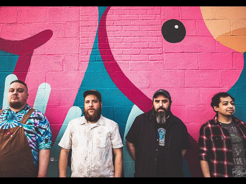 The band Alex White &amp; the Friends in front of a colorful mural.