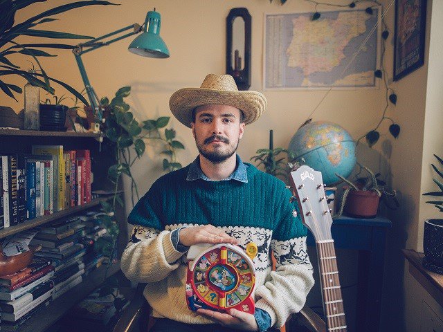 A person holding a toy in front of a bookcase.