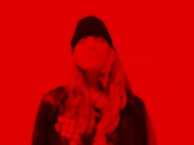 A person pictured through a filter of red.