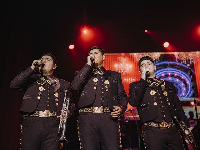 Three singers for Mariachi Herencia de México on stage.