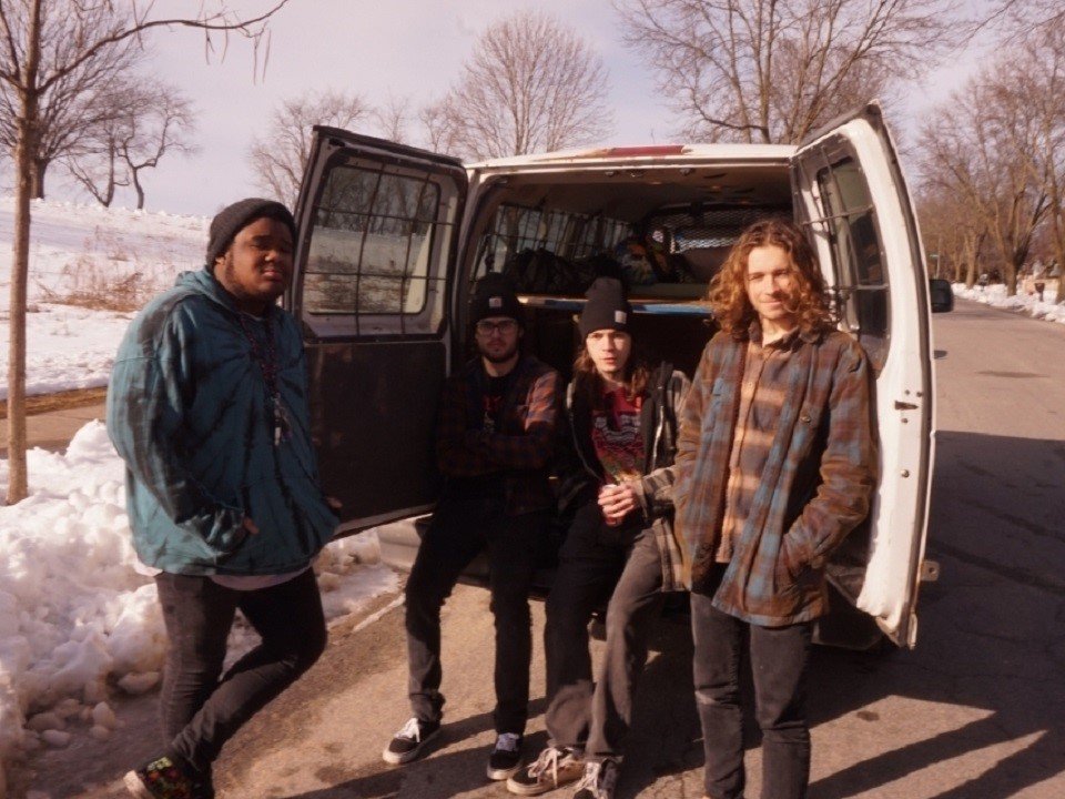 The four members of Doublespeak with a van.