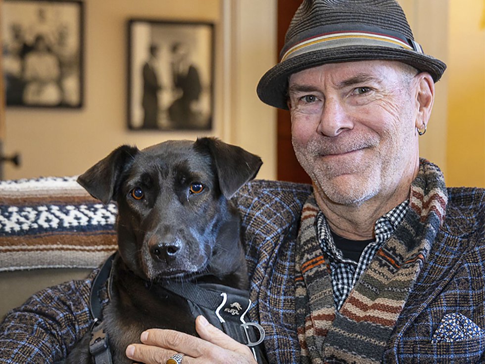Tag Evers wearing a hat and holding his dog which is some sort of black lab.