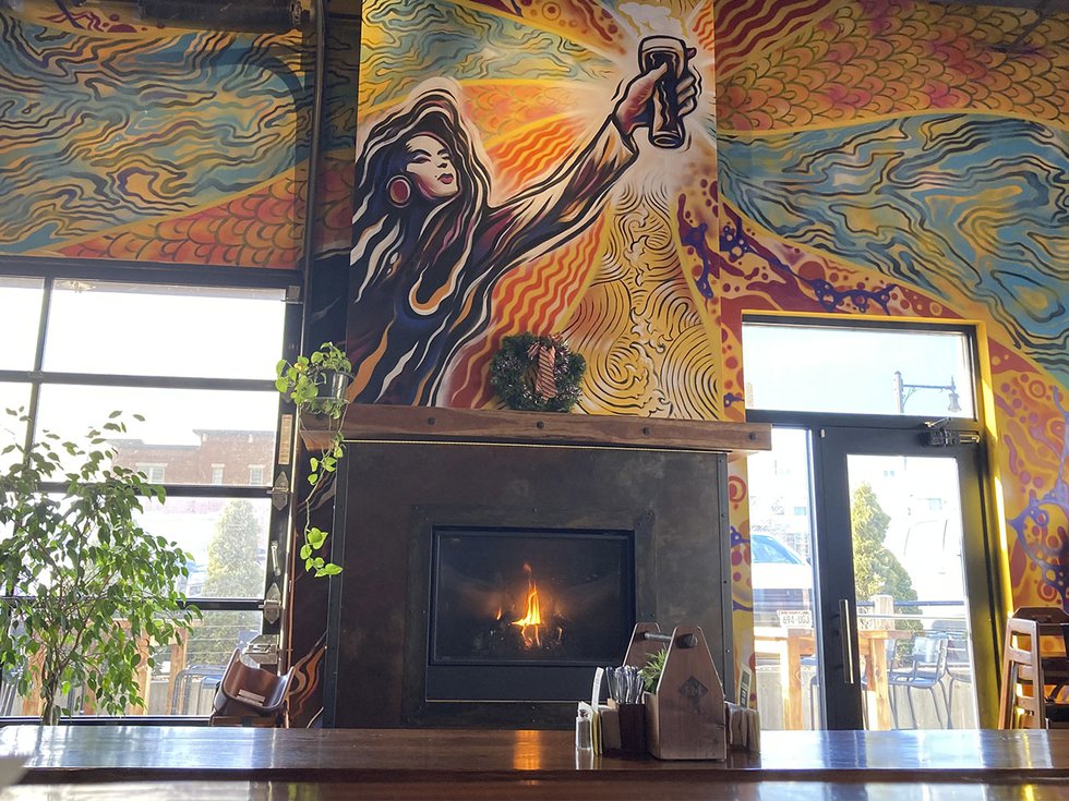 A fireplace surrounded by glass windows and a colorful mural.