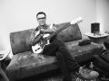 Fred Armisen and guitar sitting on a couch.