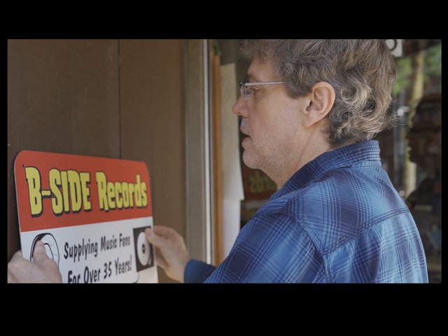 Steve Manley putting a sign on the exterior of B-Side's original location on State Street.
