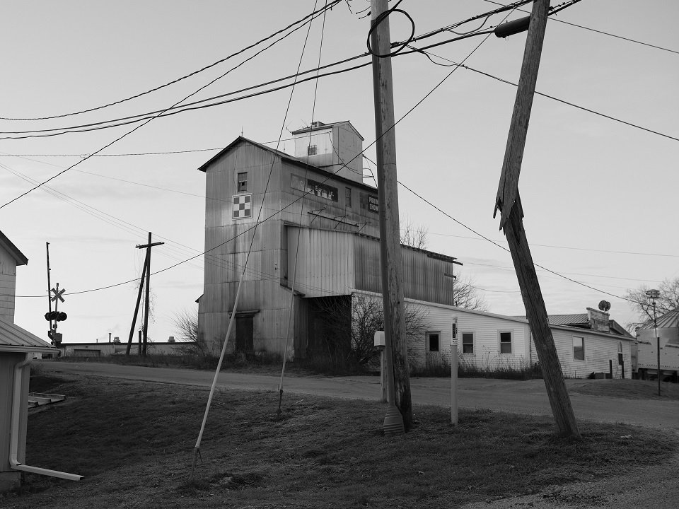 A black and white image of a building and broken telephone pole.