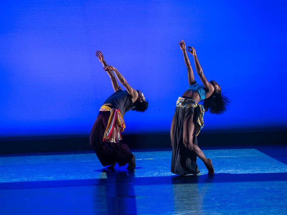 Two dancers on a blue-lit stage.