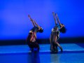 Two dancers on a blue-lit stage.