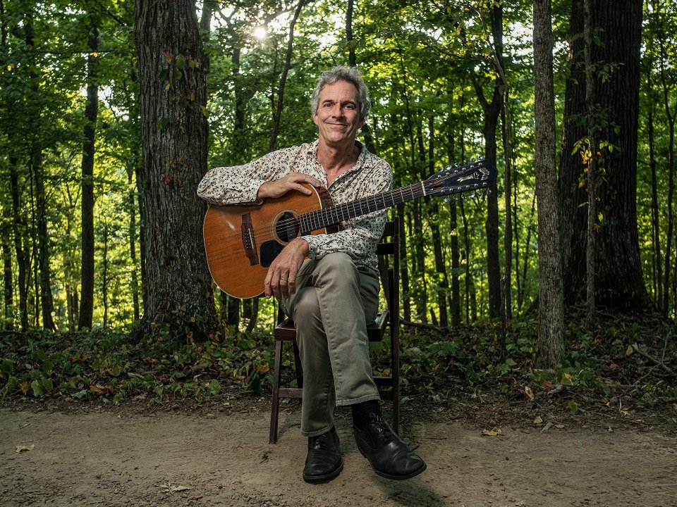 Colin O'Brien and guitar in the woods.