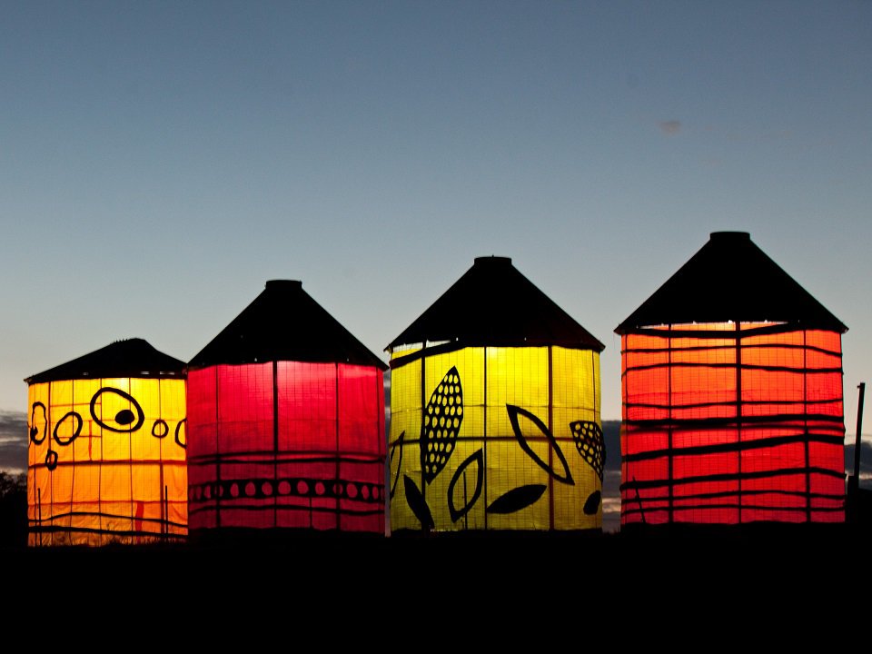 Illuminated corn cribs at dusk.