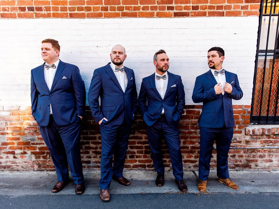 Four people in suits in front of a wall.