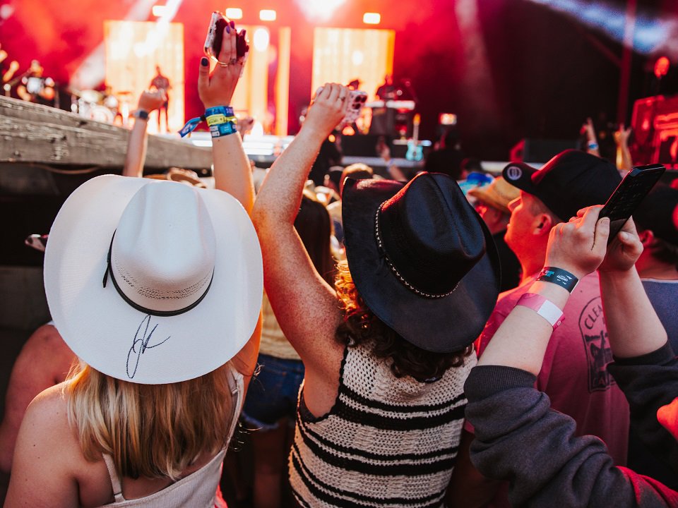 A group of people phone-filming a band on stage.