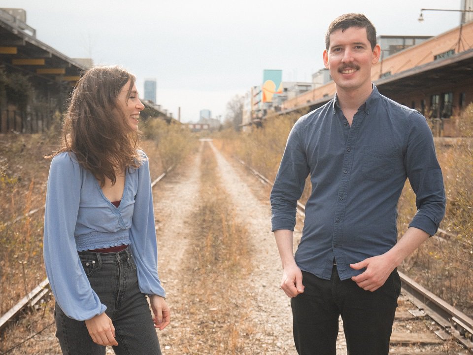 The two members of the band Rakish standing between sets of railroad tracks.