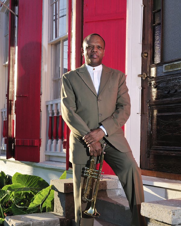 Leroy Jones and trumpet standing on the front steps of a row house.