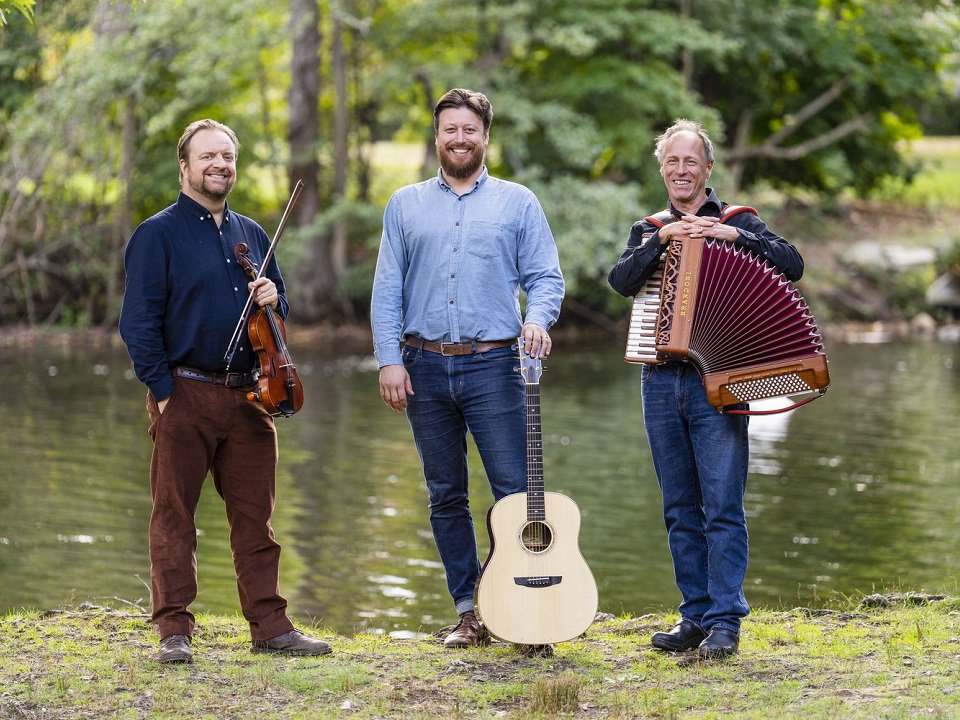 The three members of Kalos and instruments, by a river.