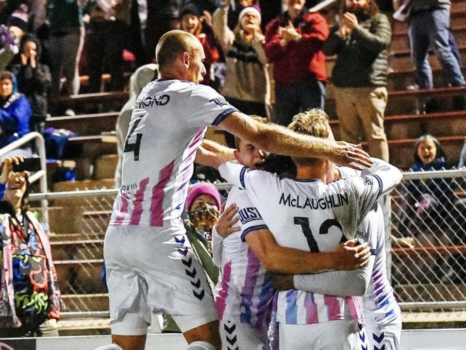 A group of people in sports uniforms embracing in celebration.