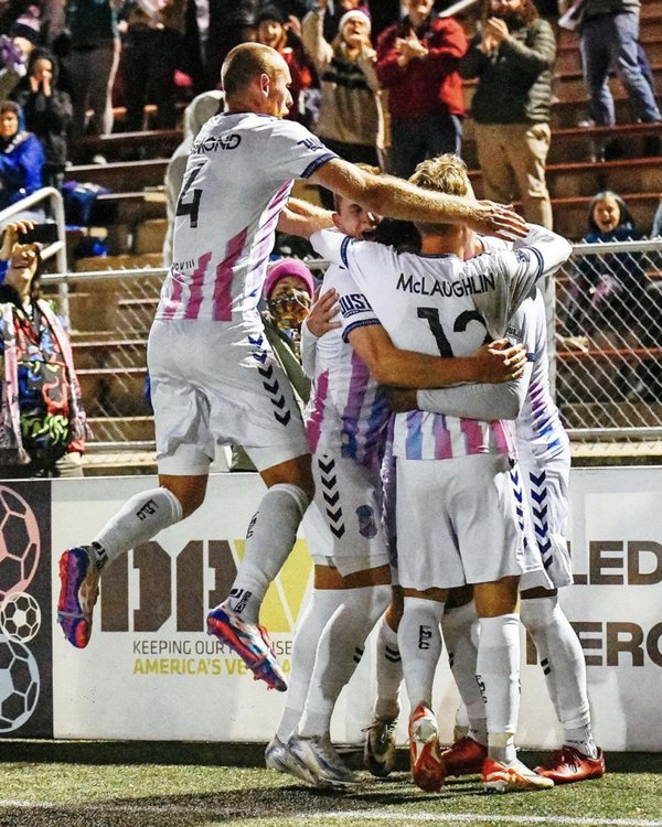 A group of people in sports uniforms embracing in celebration.