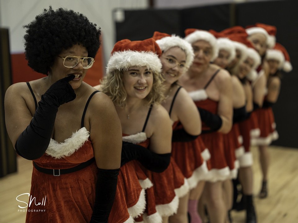 A line of dancers in red and white dresses and hats.