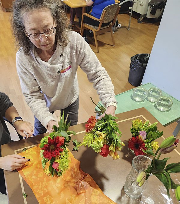 Ivy Corfis distributes flowers at Capitol Lakes Retirement Commu