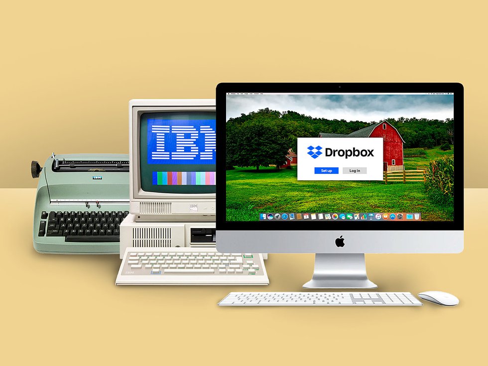 A modern iMac in front of a 1980s IBM computer and a typewriter.